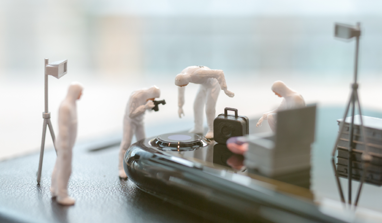 A cyber forensic team made of figurines inspecting a phone that has fallen victim to a cyber attack
