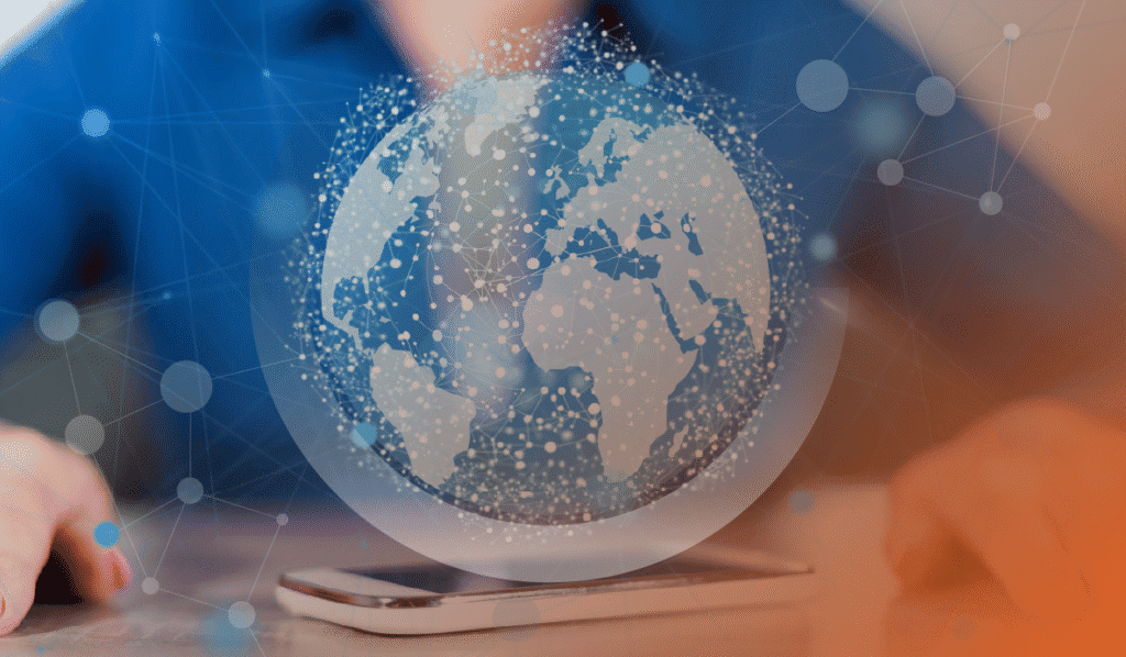 This image represents the topic of the article: "Why Smart IT Solutions for Calgary Businesses Are the Key to Secure, Accessible Information". The image colours are orange and blue. There is a person from the shoulder down, sitting at a desk, wearing a blue shirt. In front of them, is a white cell phone. There is a graphic of a globe overlaid on top of the photo, with lines and nodes representing information and IT.