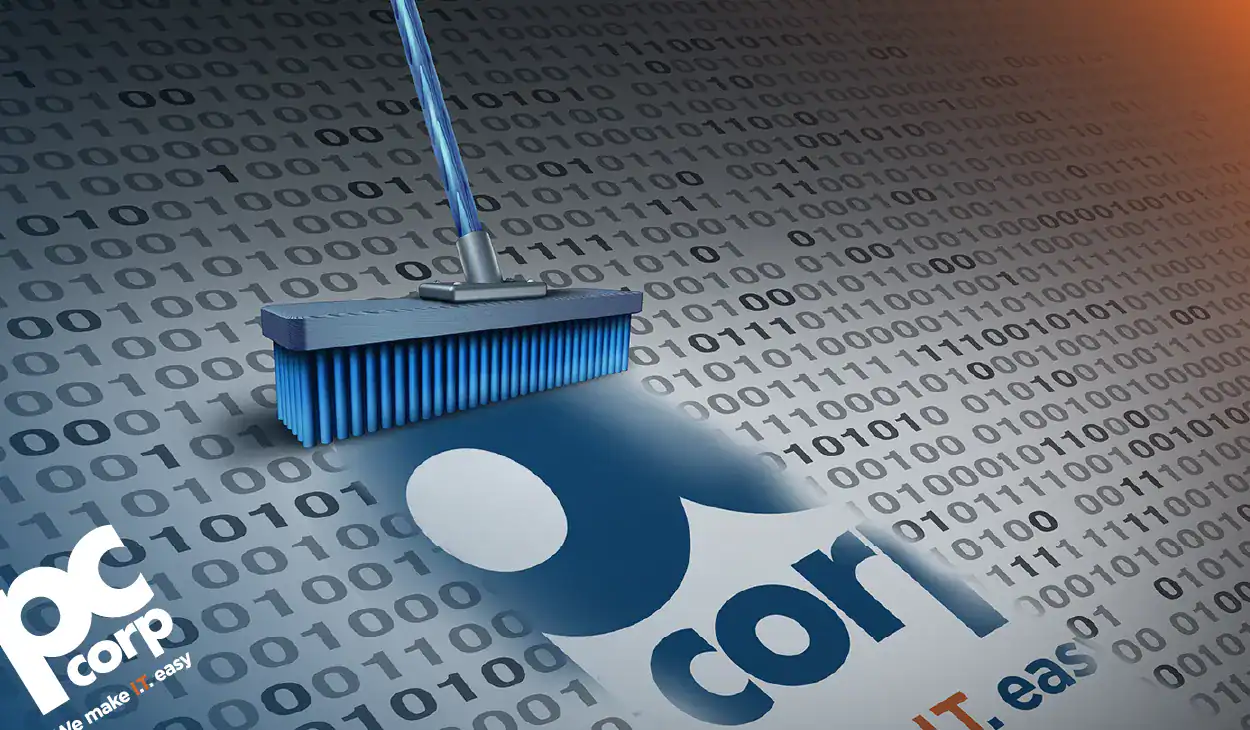 An image that represents the blog title and theme: "You Asked for AI. But Do You Actually Have Clean Data?" there is a photo of a broom cleaning up a bunch of binary computer code to reveal the PC Corp logo.
